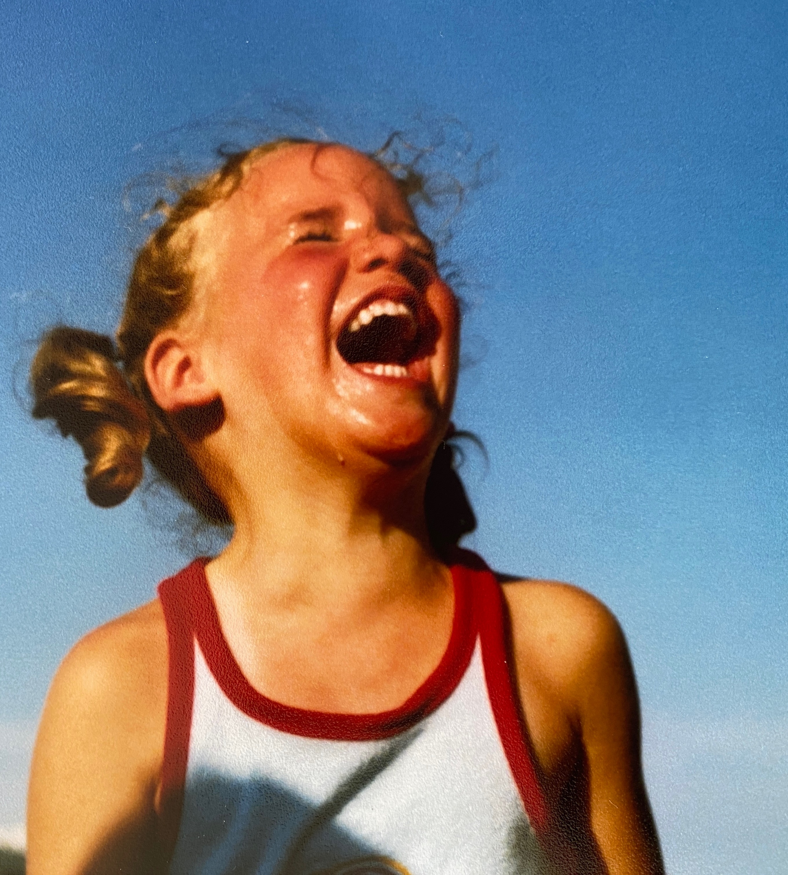 Jennifer Hayes laughing under a bright blue sky as a child